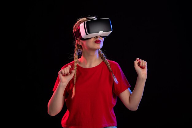 Vista frontal de la mujer joven jugando vr en la pared oscura