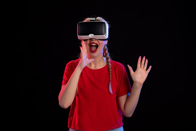 Vista frontal de la mujer joven jugando vr en la pared oscura