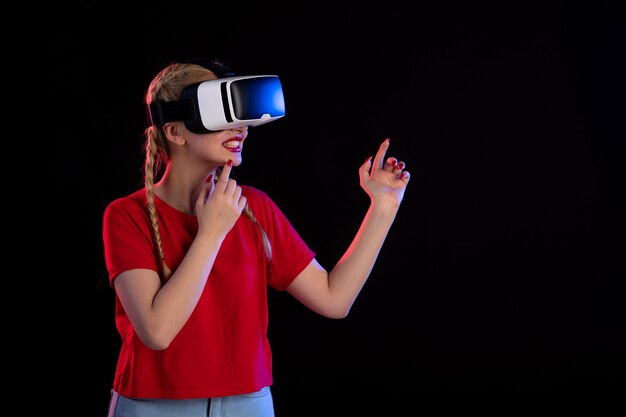 Vista frontal de la mujer joven jugando vr en la pared oscura