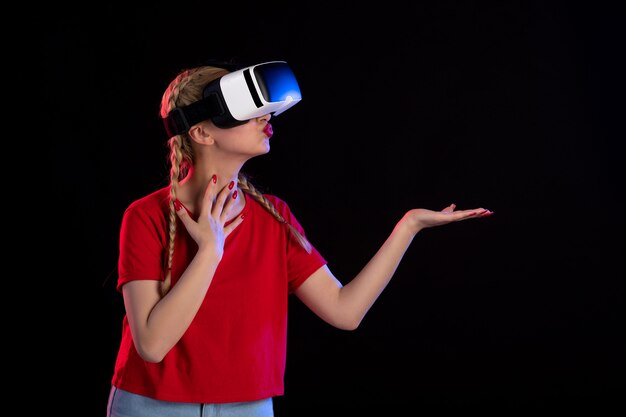 Vista frontal de la mujer joven jugando vr en la pared oscura