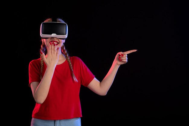 Vista frontal de la mujer joven jugando vr en la pared oscura