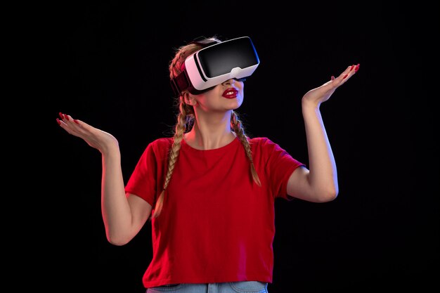 Vista frontal de la mujer joven jugando vr en la pared oscura