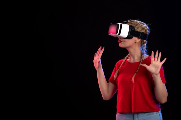 Vista frontal de la mujer joven jugando vr en la pared oscura