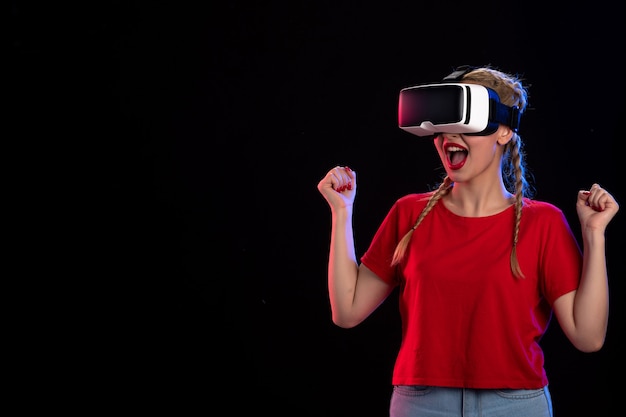 Vista frontal de la mujer joven jugando vr en la pared oscura