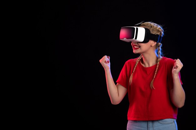 Vista frontal de la mujer joven jugando vr en la pared oscura