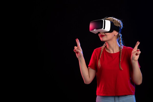 Vista frontal de la mujer joven jugando vr en la pared oscura