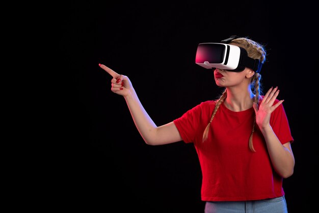 Vista frontal de la mujer joven jugando vr en visual de ultrasonido de tecnología de juego oscuro