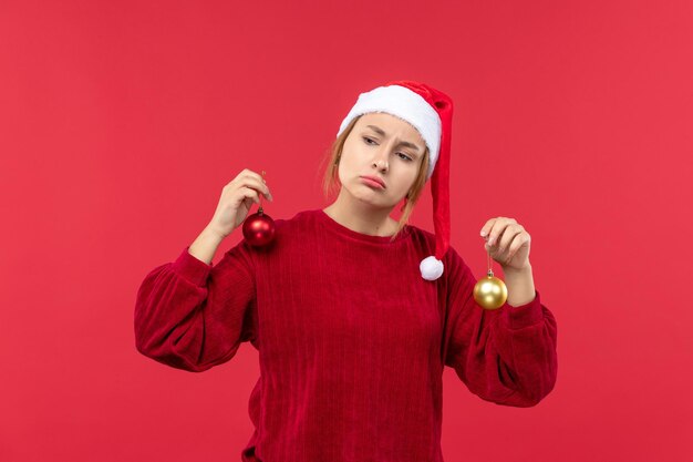 Vista frontal de la mujer joven con juguetes de Navidad en el escritorio rojo emoción de vacaciones de Navidad