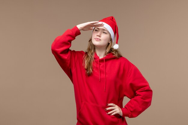 Vista frontal mujer joven mirando a distancia sobre fondo marrón vacaciones de emociones navideñas