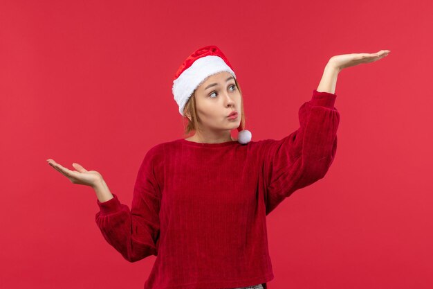 Vista frontal mujer joven mostrando algo con sus manos, rojo de vacaciones de Navidad