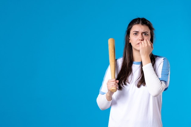 Vista frontal mujer joven nerviosa con bate de béisbol en azul