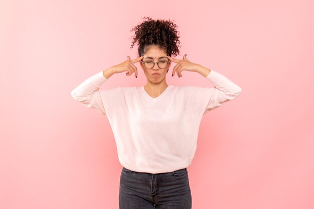 Vista frontal de la mujer joven con los ojos cerrados en la pared rosa