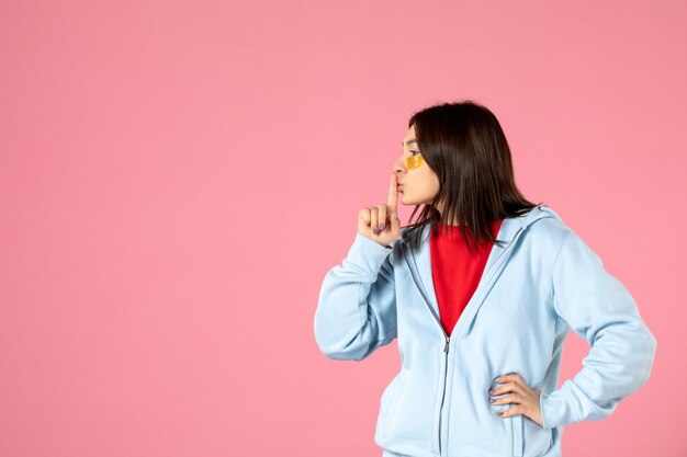 Vista frontal de la mujer joven con parches en los ojos en la pared rosa