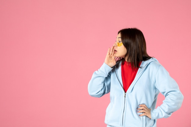 Vista frontal de la mujer joven con parches en los ojos en la pared rosa