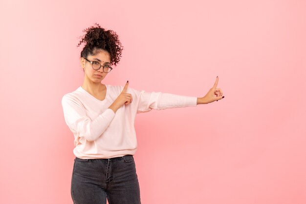 Vista frontal de la mujer joven en la pared rosa