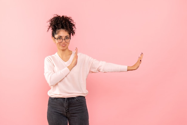 Foto gratuita vista frontal de la mujer joven en la pared rosa