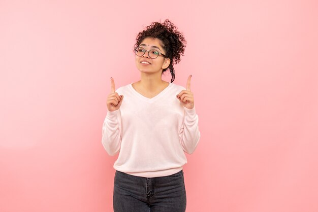 Vista frontal de la mujer joven en la pared rosa