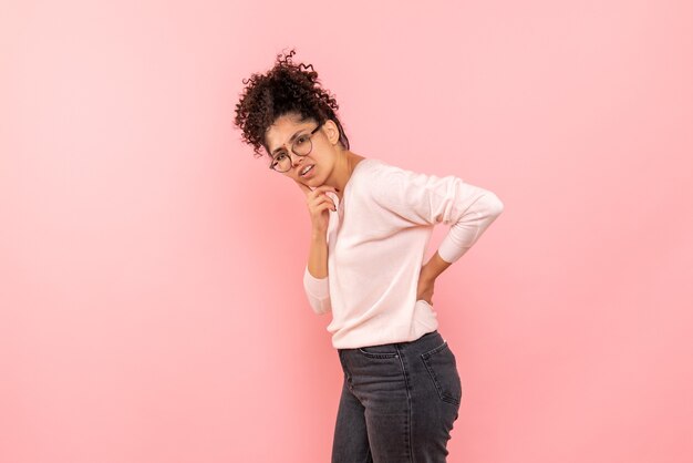 Vista frontal de la mujer joven pensando en la pared rosa