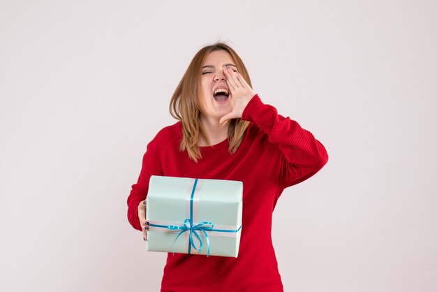 Vista frontal mujer joven de pie con presente de Navidad gritando