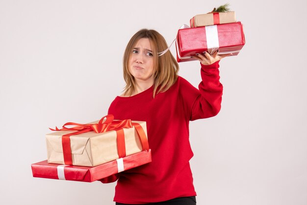 Vista frontal mujer joven de pie con regalos en sus manos