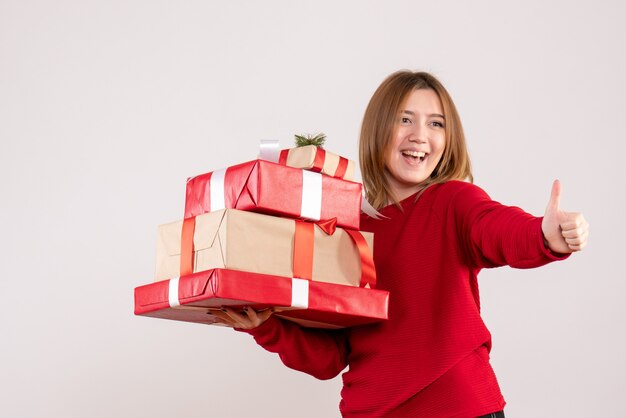 Vista frontal mujer joven de pie con regalos en sus manos