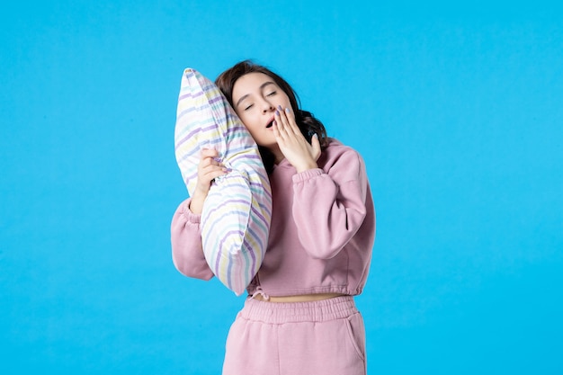 Foto gratuita vista frontal mujer joven en pijama rosa sosteniendo la almohada en la pared azul noche color reposo en cama emoción sueño mujer sueño