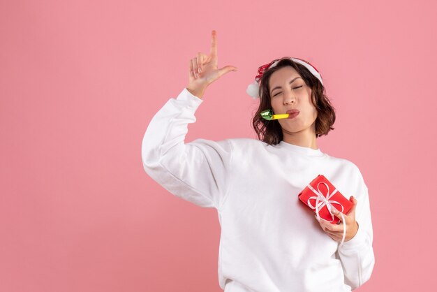 Foto gratuita vista frontal de la mujer joven con poco presente de navidad en la pared rosa