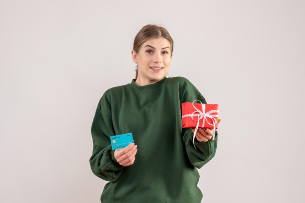 Vista frontal mujer joven con poco presente de Navidad y tarjeta bancaria