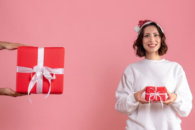 Vista frontal de la mujer joven con poco presente y no aceptar el regalo del hombre en la pared rosa