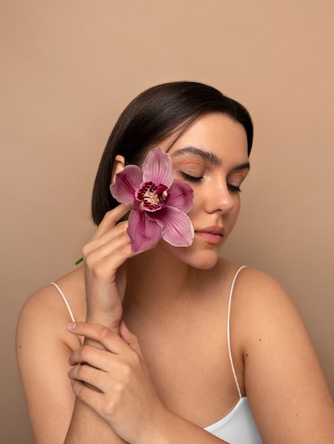 Foto gratuita vista frontal mujer joven posando con flor