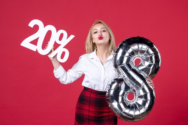 Vista frontal mujer joven posando con globo plateado y escribiendo sobre fondo rojo femenino cariñoso feminidad igualdad compras sensuales