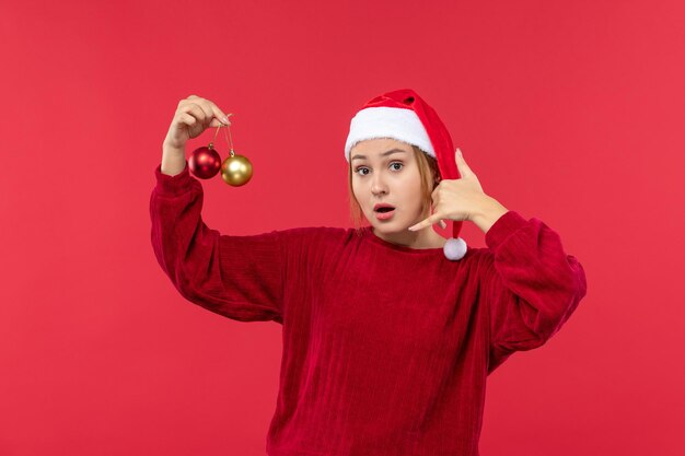 Vista frontal mujer joven posando con juguetes navideños, emoción navideña de vacaciones