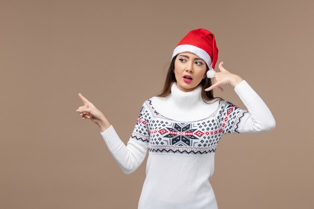 Vista frontal mujer joven posando sobre fondo marrón emoción de vacaciones de Navidad