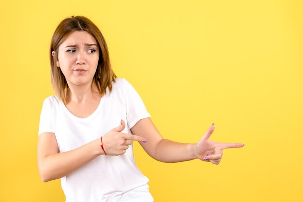 Vista frontal, de, mujer joven, posar, en, pared amarilla