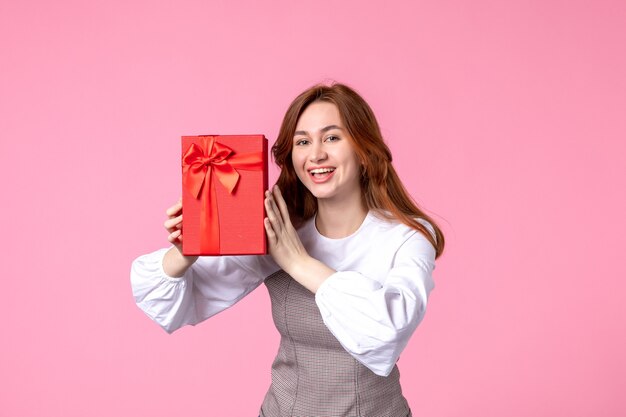 Vista frontal mujer joven con presente en paquete rojo sobre fondo rosa fecha de amor marzo horizontal sensual regalo perfume mujer foto dinero