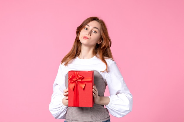 Vista frontal mujer joven con presente en paquete rojo sobre fondo rosa fecha de amor marzo horizontal sensual regalo perfume mujer foto igualdad