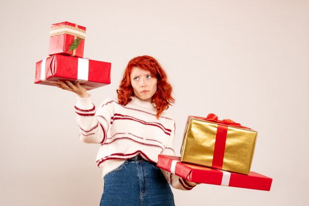 Vista frontal, de, mujer joven, proceso de llevar, navidad, regalos, en, pared blanca