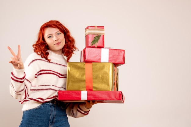 Foto gratuita vista frontal, de, mujer joven, proceso de llevar, navidad, regalos, en, pared blanca