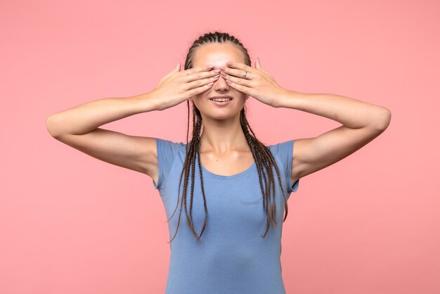 Vista frontal de la mujer joven que cubre sus ojos en rosa