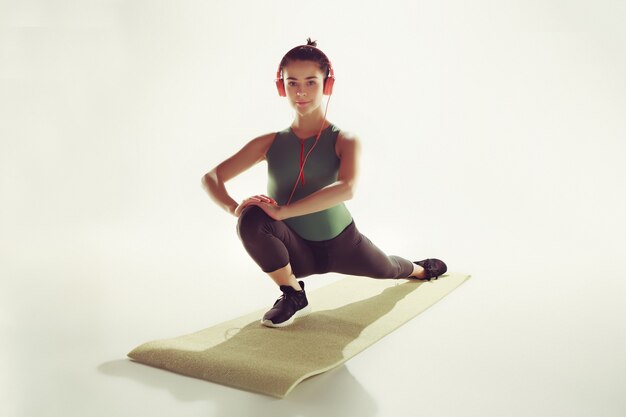 Vista frontal de una mujer joven que estira el cuerpo en la clase de gimnasia.