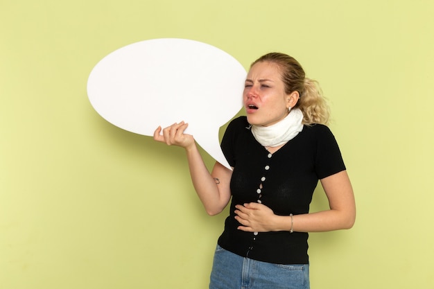 Foto gratuita vista frontal mujer joven que se siente muy enferma y enferma con un enorme cartel blanco y su estómago en la pared verde enfermedad medicina salud enfermedad