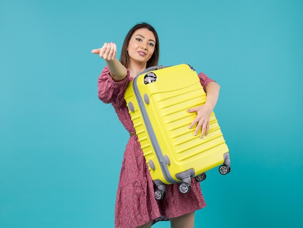 Vista frontal mujer joven que va de vacaciones y que sostiene una bolsa grande en el fondo azul viaje mar vacaciones viaje mujer en el extranjero