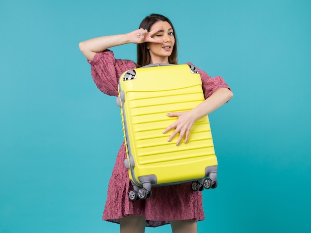 Vista frontal mujer joven que va de vacaciones y que sostiene una bolsa grande en el fondo azul viaje mar vacaciones viaje mujer en el extranjero