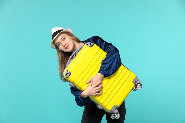 Vista frontal de la mujer joven que va de vacaciones y que sostiene una bolsa grande sobre fondo azul, viaje, viaje, vacaciones, viaje por mar, avión