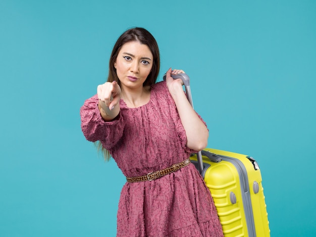 Vista frontal mujer joven que va de vacaciones con su bolsa amarilla en el fondo azul viaje verano viaje mujer mar humano