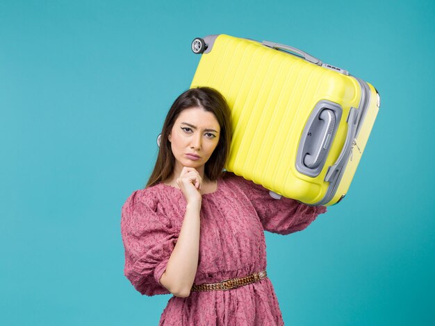 Vista frontal de la mujer joven que va de vacaciones con su gran bolsa sobre fondo azul viaje de verano mujer viaje de vacaciones