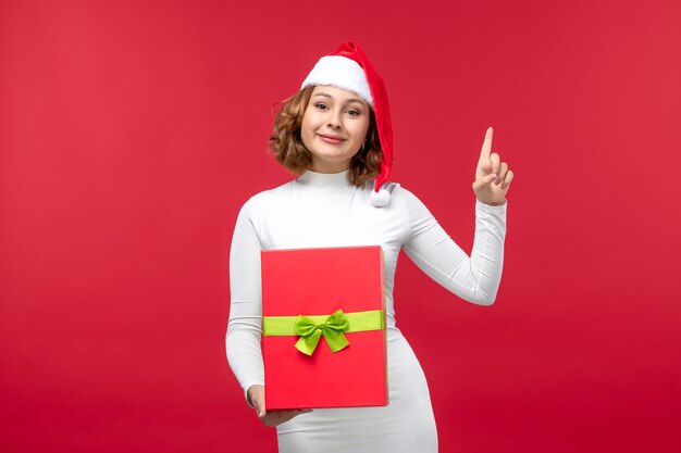 Vista frontal de la mujer joven con regalo de Navidad en rojo