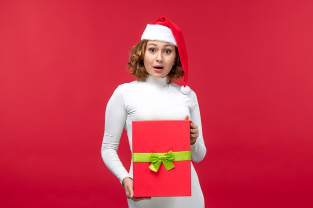 Vista frontal de la mujer joven con regalo de Navidad en rojo