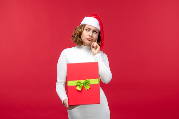 Vista frontal de la mujer joven con regalo de Navidad en rojo