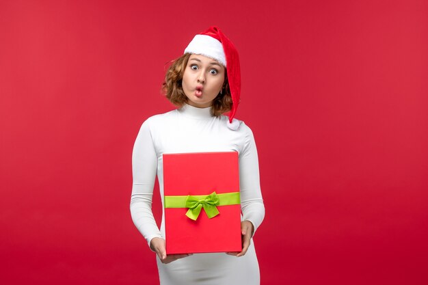 Vista frontal de la mujer joven con regalo de Navidad en rojo